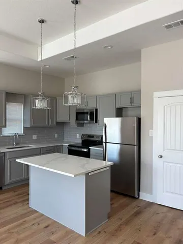 a kitchen with a refrigerator a sink and dishwasher with wooden floor