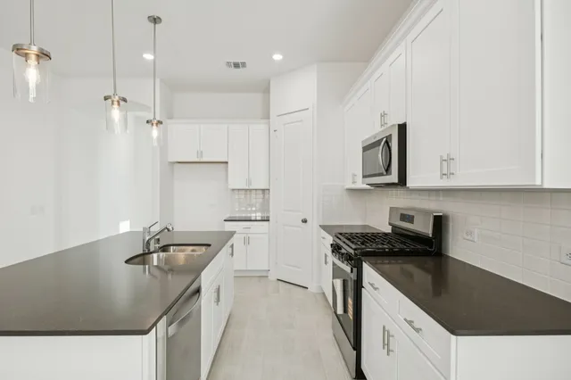 a kitchen with stainless steel appliances granite countertop a sink stove and refrigerator