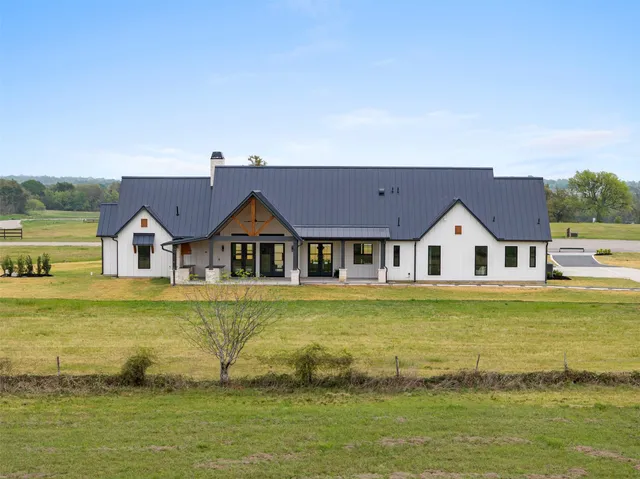 a view of a house with a big yard and large trees