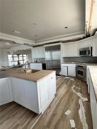 a large kitchen with stainless steel appliances a large counter top a stove a sink and a refrigerator