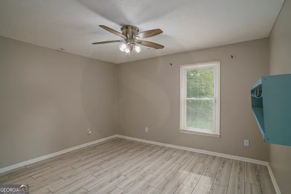 an empty room with wooden floor fan and windows