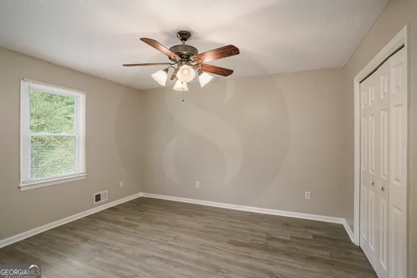 a view of an empty room with wooden floor and a window