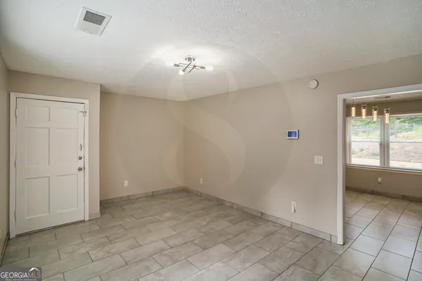 an empty room with chandelier fan and windows