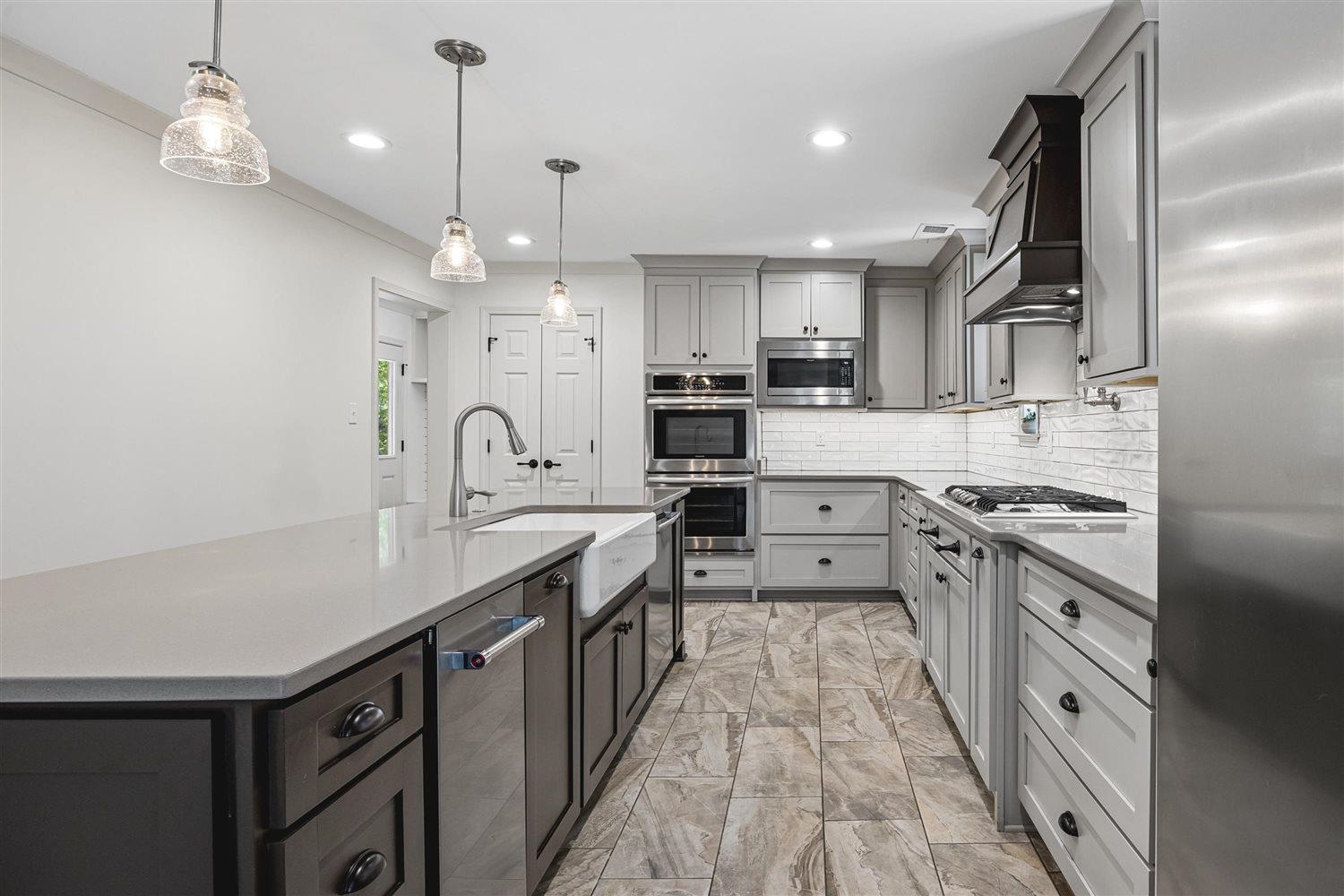 8970 Farmoor Road Germantown, TN 38139 - Photo 9 of 35 Kitchen featuring light gray cabinetry, stainless steel appliances, white subway tile backsplash, a central island with a farmhouse sink, and wood-finish flooring