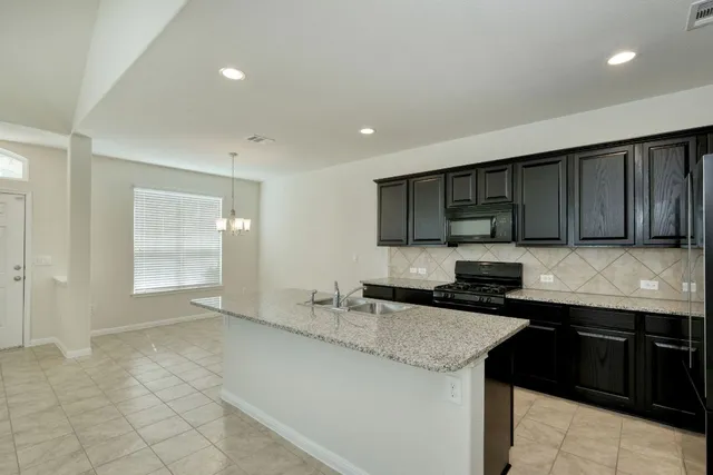 a kitchen with stainless steel appliances granite countertop a sink and a stove top oven with wooden floor