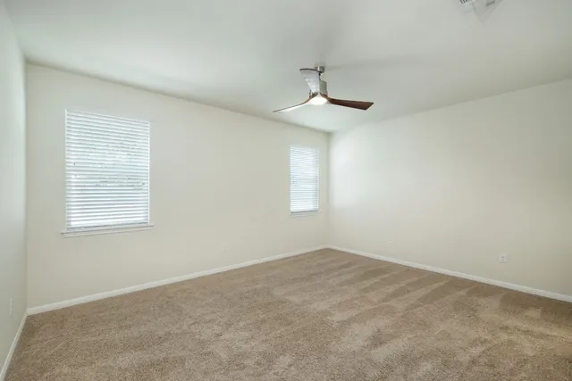 an empty room with a window and a ceiling fan