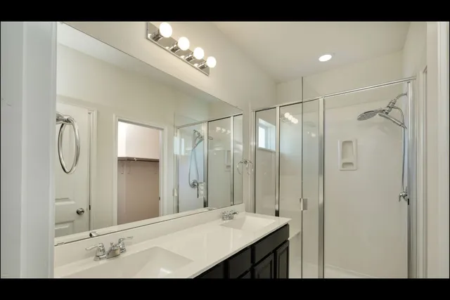 a bathroom with a double vanity sink mirror and shower