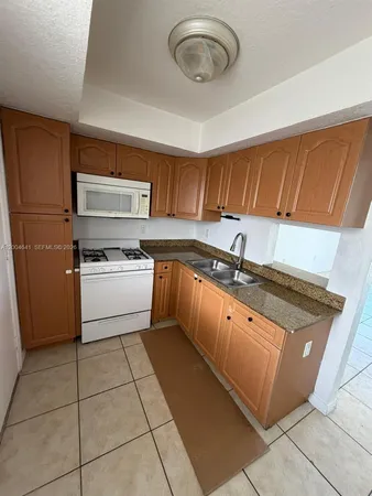 a kitchen with granite countertop a sink a stove and cabinets