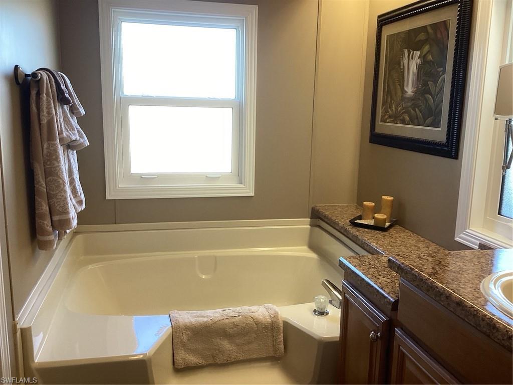 225 Belle Isle Circle Naples, FL 34112 - Photo 18 of 48 a bathroom with a tub a sink and a window