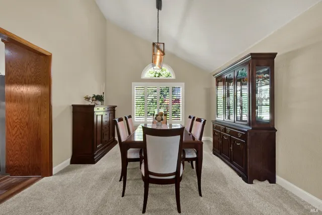 a kitchen with stainless steel appliances kitchen island granite countertop a refrigerator a stove top oven and a dining table with wooden floor