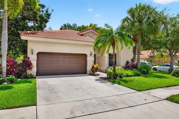 a front view of a house with a garden and palm trees