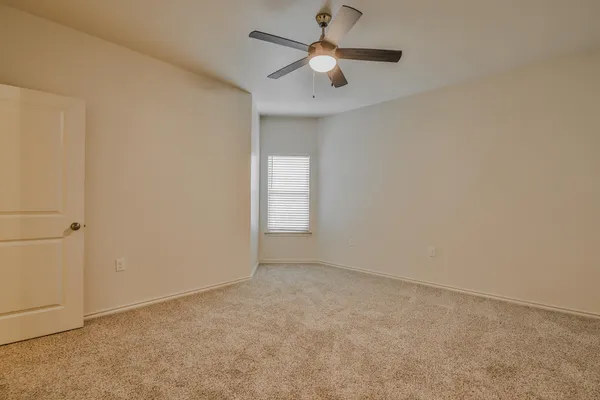 an empty room with a window and a fan