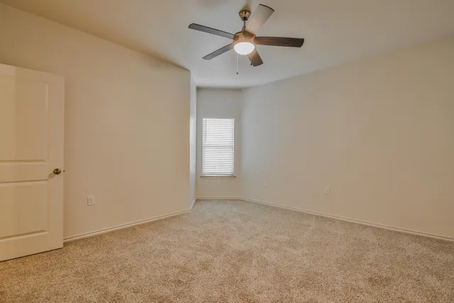 an empty room with a window and a fan