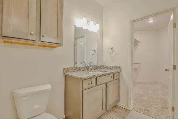 a bathroom with a granite countertop sink and a toilet