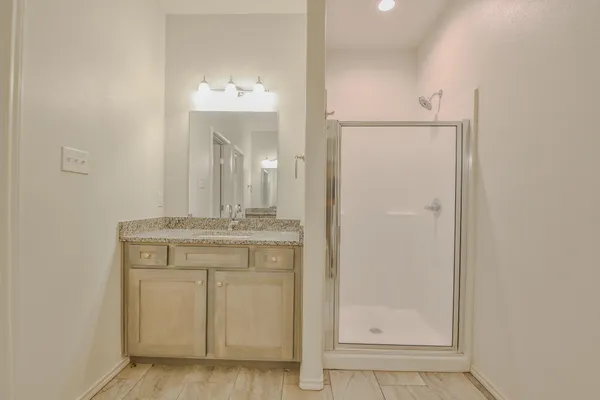 a bathroom with a granite countertop sink a mirror and a shower