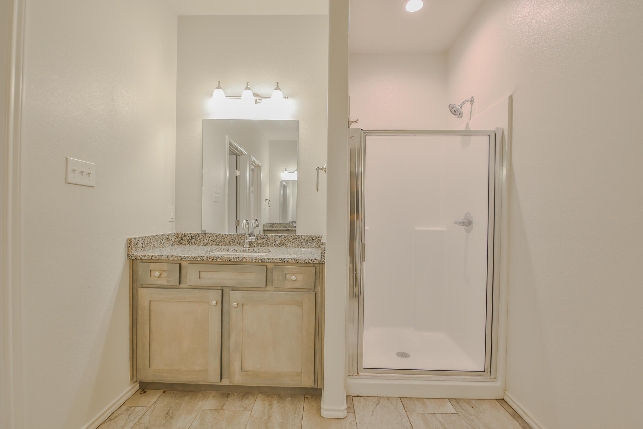 5508 Kemper Street Lubbock, TX 79416 - Photo 25 of 26 a bathroom with a granite countertop sink a mirror and a shower