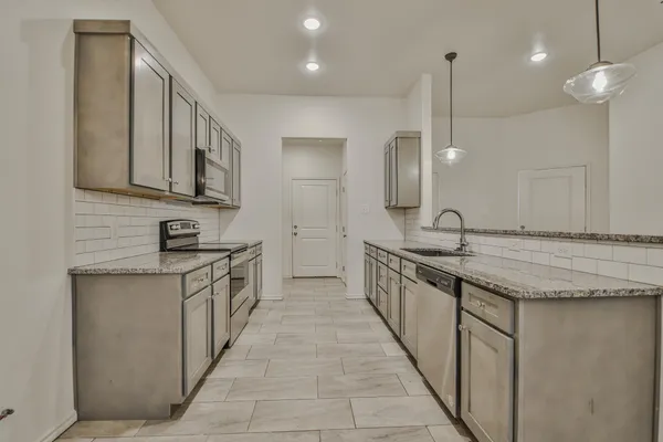 a large kitchen with granite countertop a sink and a stove