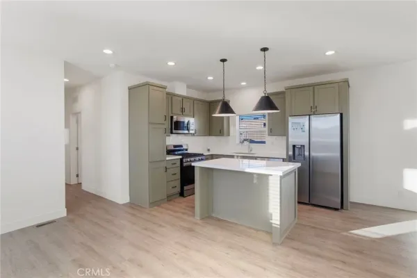 a kitchen with stainless steel appliances granite countertop a sink a stove and a wooden floors