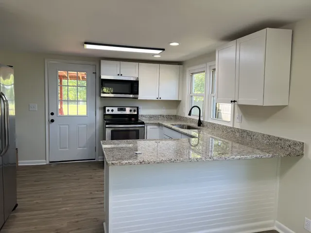 a kitchen with stainless steel appliances granite countertop a sink a stove and a refrigerator