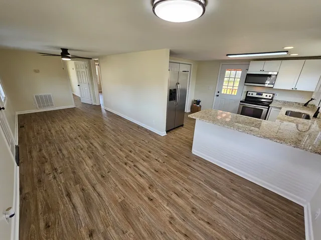 a living room with stainless steel appliances furniture a refrigerator and a kitchen view