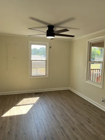 an empty room with wooden floor and windows