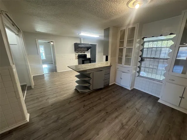 a view of an empty room with wooden floor and windows