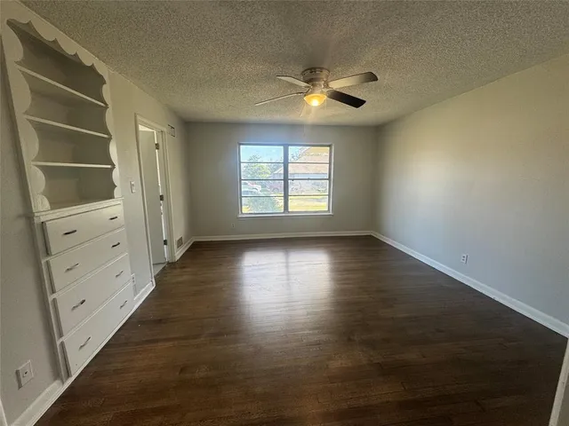 an empty room with wooden floor chandelier fan and windows