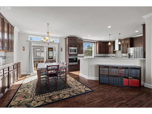 a living room with stainless steel appliances kitchen island granite countertop a dining table chairs and granite counter tops