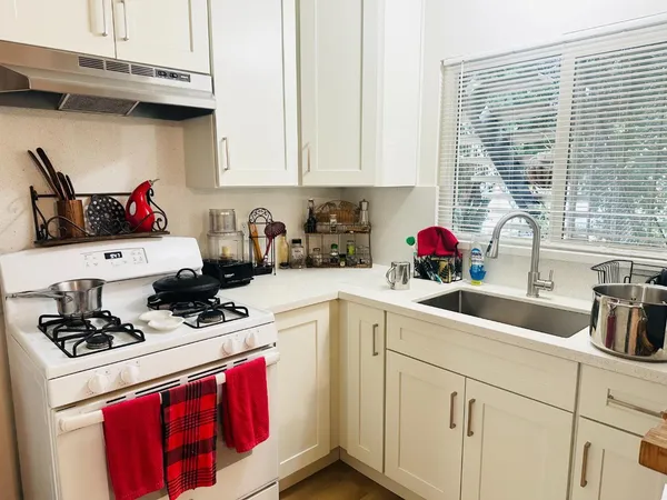 a kitchen with stainless steel appliances granite countertop a sink dishwasher and white cabinets with wooden floor