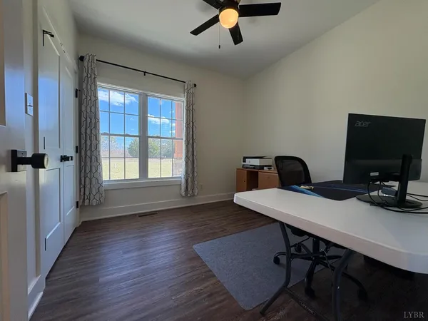 a view of empty room with wooden floor and fan