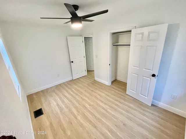 an empty room with wooden floor and a ceiling fan