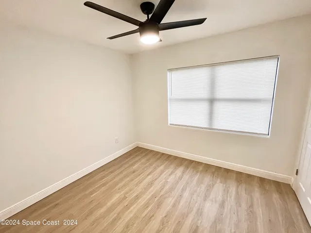 an empty room with a window and a ceiling fan