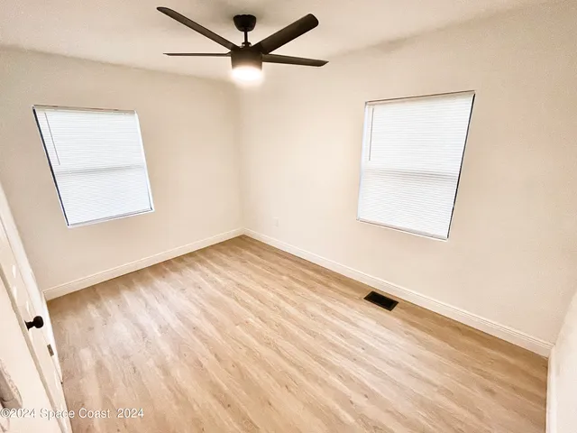 an empty room with a window and a ceiling fan