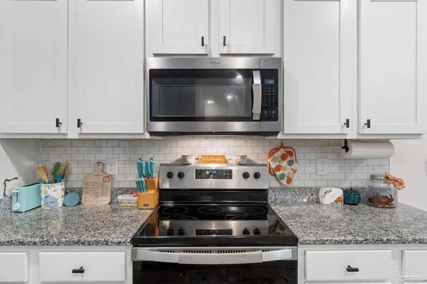a kitchen with granite countertop white cabinets and stainless steel appliances