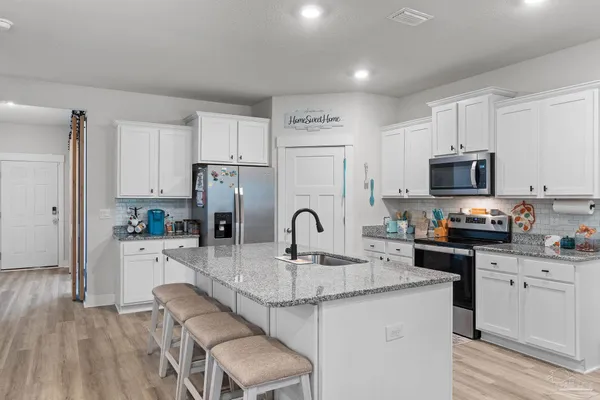 a kitchen with granite countertop a sink cabinets a refrigerator and a stove