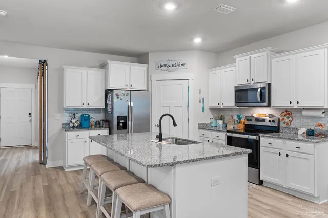 a kitchen with granite countertop a sink cabinets a refrigerator and a stove