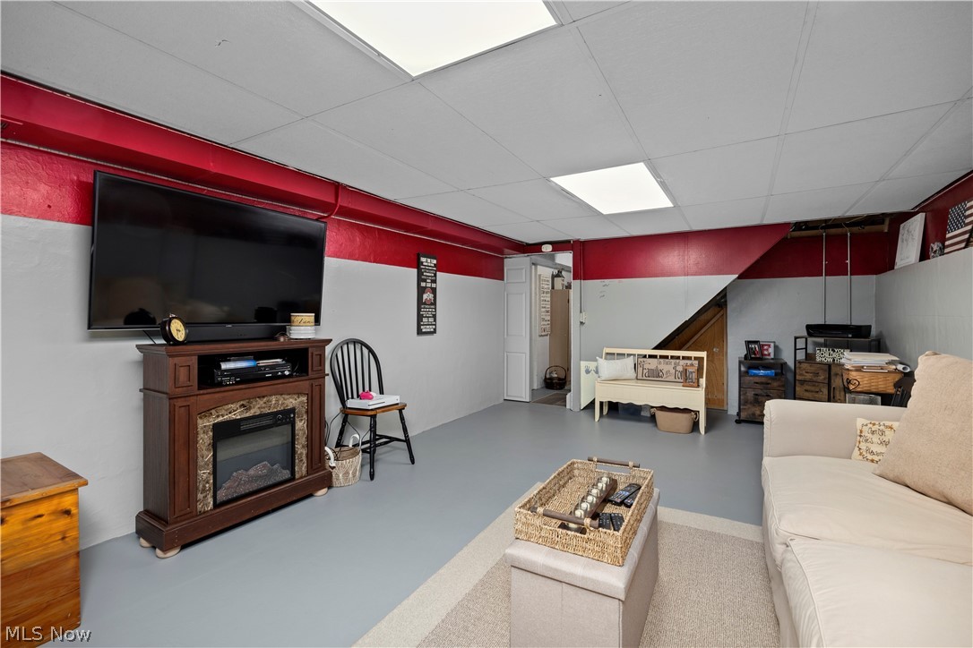 965 Gulf Road Elyria, OH 44035 - Photo 26 of 37 Basement family room with concrete flooring, a paneled ceiling, and a glass covered fireplace