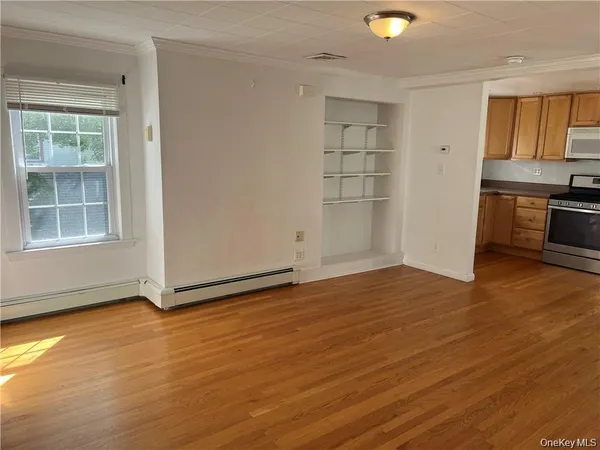 an empty room with wooden floor and cabinet