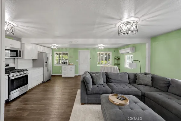 a living room with furniture a chandelier and kitchen view
