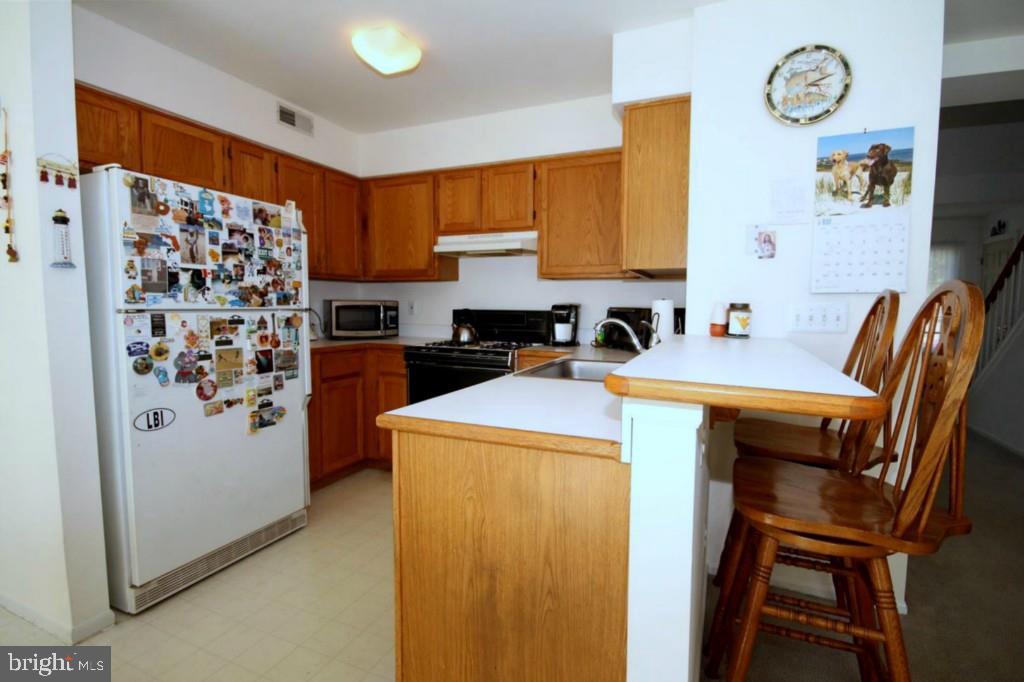 228 Schooner Road Manahawkin, NJ 08050 - Photo 7 of 19 a view of kitchen with stainless steel appliances granite countertop a refrigerator and a stove top oven