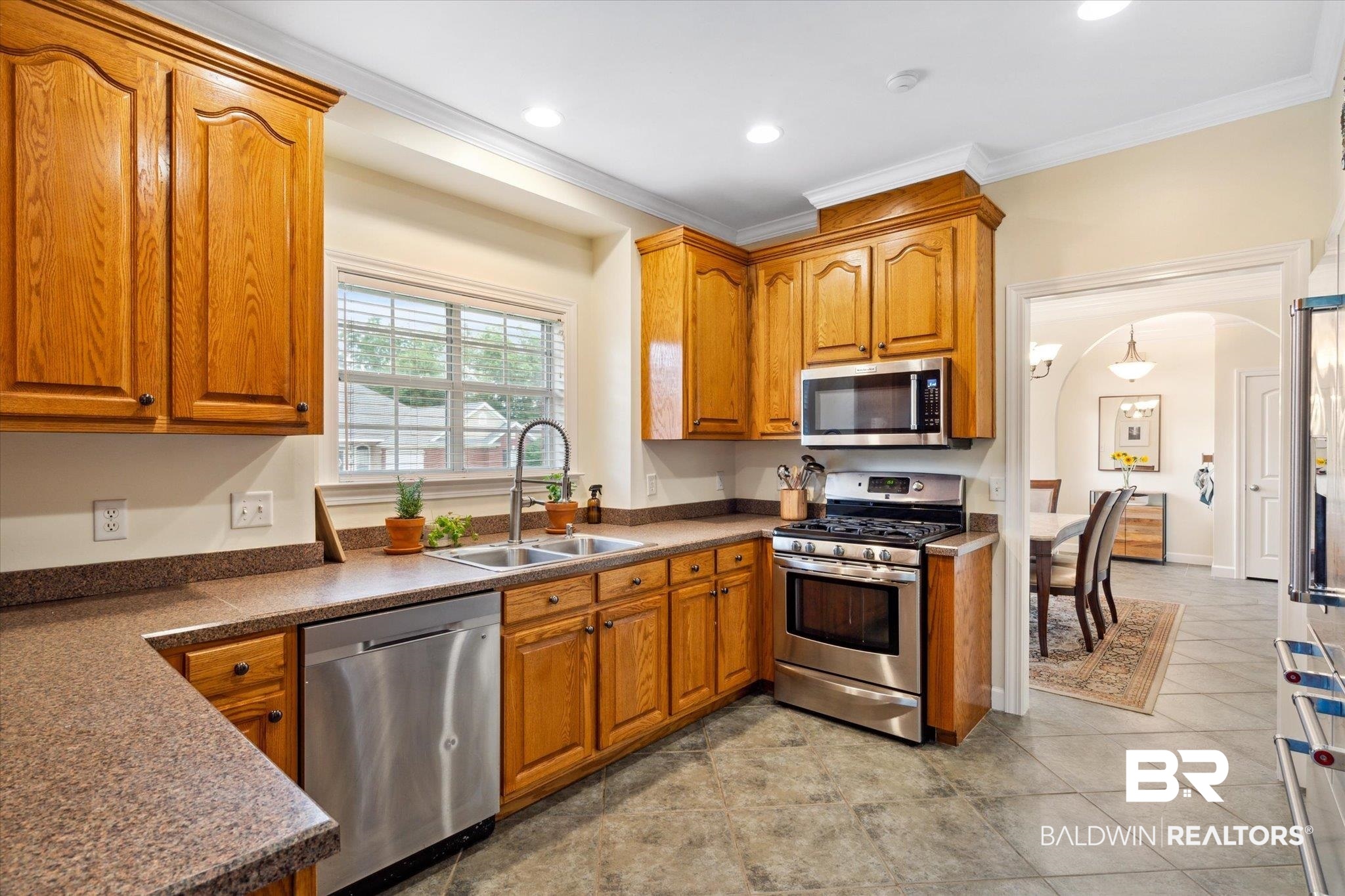 1561 William Dunn Way Mobile, AL 36695 - Photo 8 of 28 Kitchen with sink, appliances with stainless steel finishes, crown molding, and light tile patterned floors