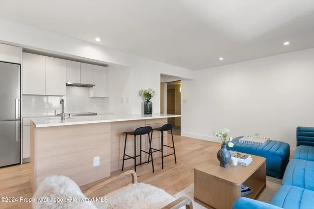 a kitchen with stainless steel appliances granite countertop a sink a stove a dining table and chairs with wooden floor