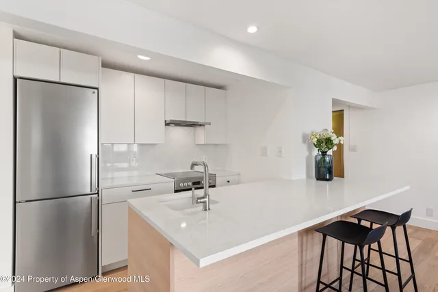 a kitchen with a sink a refrigerator and cabinets