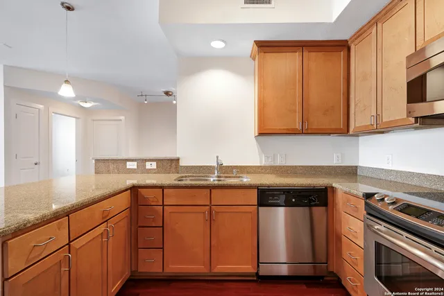 a kitchen with granite countertop wooden cabinets stainless steel appliances and a sink