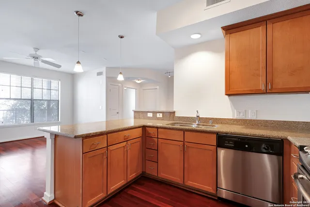 a kitchen with stainless steel appliances granite countertop a sink and cabinets with wooden floor
