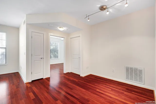 a view of empty room with wooden floor and fan