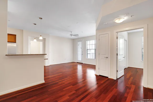 a view of empty room with wooden floor and fan
