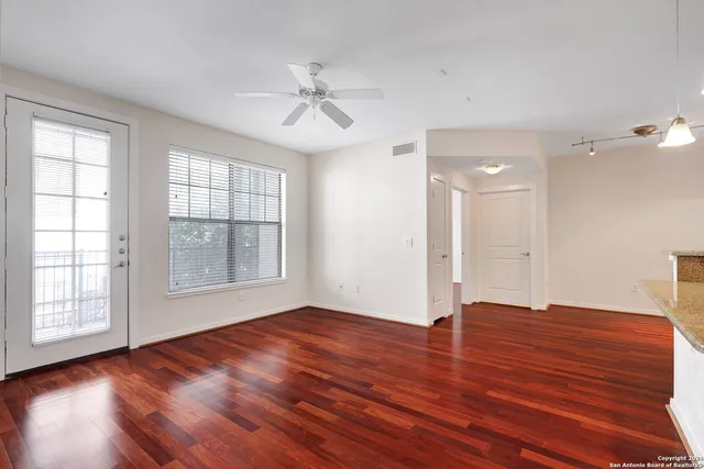 a view of an empty room with wooden floor and a window