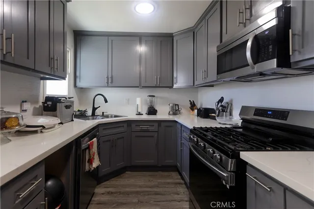 a kitchen with stainless steel appliances granite countertop a stove a sink dishwasher and a microwave oven with wooden cabinets