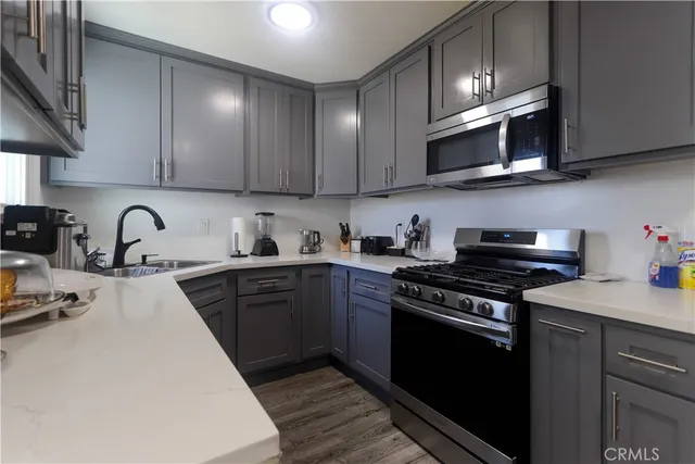 a kitchen with stainless steel appliances granite countertop a sink a stove top oven and cabinets